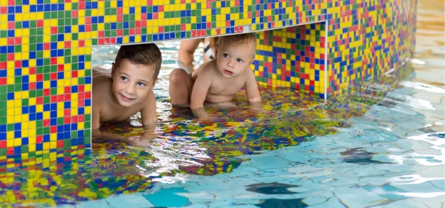 Zwei kleine Kinder im seichten Wasser gucken neugierig.