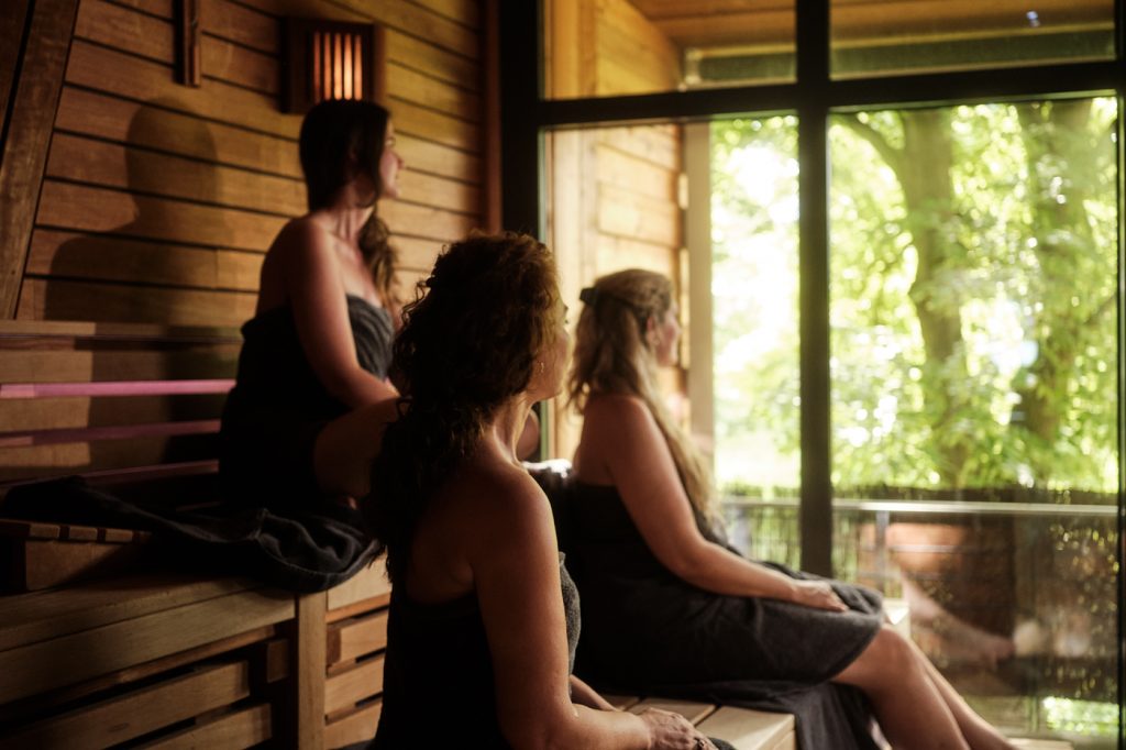 Drei Frauen sitzen in einem Saunaraum und gucken Richtung Fenster