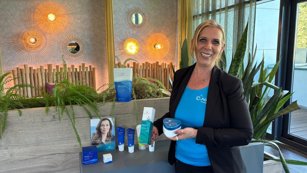 Verkäuferin präsentiert lächelnd verschiedene Kosmetik-Produkte