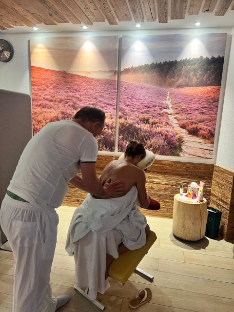 Eine Frau bekommt in gemütlicher Umgebung eine Rückenmassage von einem Mann